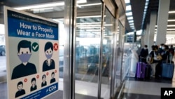 FILE - A sign about face mask rules is displayed at O'Hare International Airport in Chicago, July 2, 2021.
