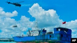 Helikopter menjatuhkan kontainer berisi peralatan pompa minyak ke dek FV Lu Rong Yuan Yu, kapal penangkap ikan berbendera China yang kandas, di Pointe-aux Sables, Port-Louis, Mauritius, Selasa 9 Maret 2021. (Beekash Roopun/L'express Maurice via AP/ilustrasi)