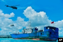 Sebuah helikopter menjatuhkan kargo berisi peralatan pemompaan minyak ke dek FV Lu Rong Yuan Yu, kapal penangkap ikan berbendera China yang kandas, di Pointe-aux Sables, Port-Louis, Mauritius, Selasa 9 Maret 2021. (Foto: via AP)