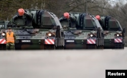 A soldier stands in front of Howitzers of the German armed forces Bundeswehr before they are loaded onto trucks to Lithuania at the Bundeswehr military base in Munster, Germany, Feb. 14, 2022.