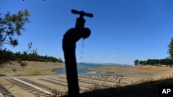 In this file photo, water drips from a faucet near boat docks sitting on dry land at the Browns Ravine Cove area of drought-stricken Folsom Lake in Folsom, Calif., on May 22, 2021. (AP Photo/Josh Edelson, File)
