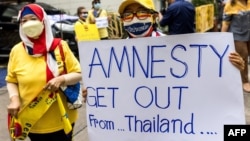 FILE - A royalist supporter holds a sign during a demonstration in Bangkok on November 25, 2021, calling for the human rights organization Amnesty International to stop operations in Thailand.
