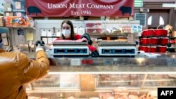 FILE - A customer pays for a cut of meat at Union Meat Company in Eastern Market in Washington, on Feb. 8, 2022.