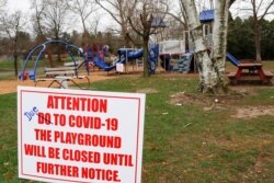 A sign with corrected spelling tells visitors the playground at the Community Park is closed until further notice due to COVID-19 on March 27, 2020, in Zelienople, Pa.