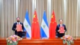 In this photo released by China’s Xinhua News Agency, Laureano Ortega Murillo, son of and advisor to Nicaraguan President Daniel Ortega, left, and Chinese Vice Foreign Minister Ma Zhaoxu display their jointly signed communique on the resumption of diploma