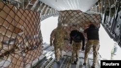 British service members unload assistance for Ukraine, delivered by the Royal Air Force, at the Boryspil International Airport outside Kyiv, Ukraine, Feb. 9, 2022.