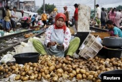 Seorang perempuan tampak mengupas kentang untuk dijual di salah satu pasar yang berlokasi dekat lintasan kereta api di Jakarta Barat, pada 1 Maret 2016. (Foto: Reuters/Garry Lotulung)