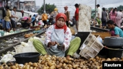 Seorang perempuan tampak mengupas kentang untuk dijual di salah satu pasar yang berlokasi dekat lintasan kereta api di Jakarta Barat, pada 1 Maret 2016. (Foto: Reuters/Garry Lotulung)