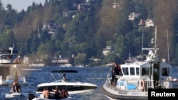 Seattle Fire Department personnel, police officers and civilians search for a missing swimmer who possibly drowned in Andrews Bay of Lake Washington, at Seward Park during a heat wave in Seattle, Washington, June 26, 2021.