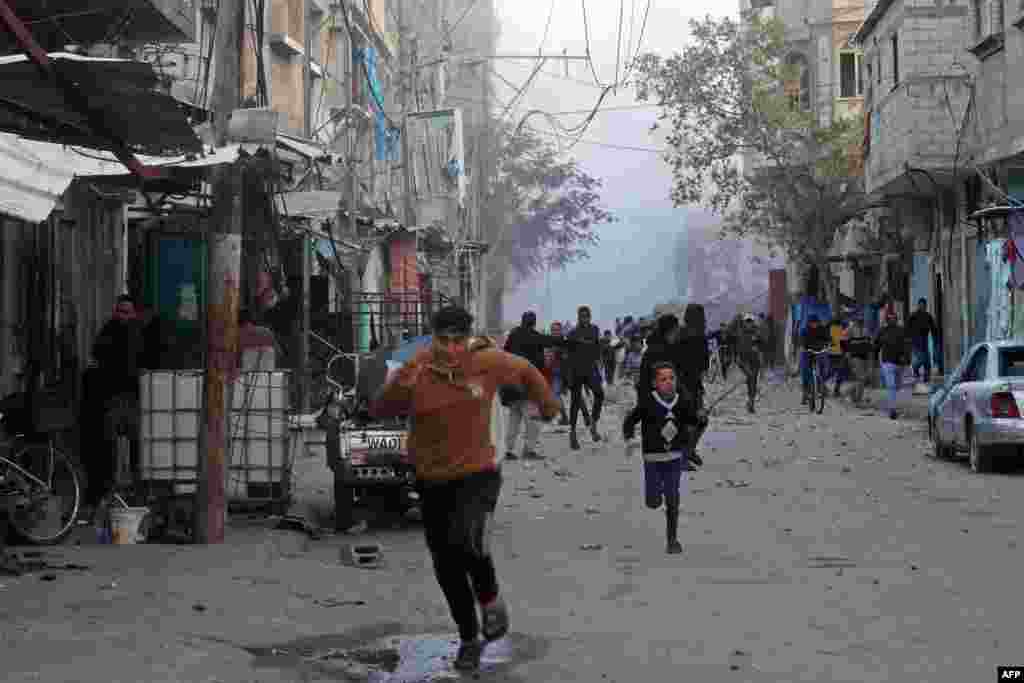 People run for cover as smoke rises from a building destroyed in Israeli airstrike at the Bureij camp for Palestinian refugees in the central Gaza Strip as the war between Israel and Hamas militants continues.