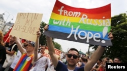 FILE - A group of Russian gays, seeking asylum in Germany because of their sexual orientation, take part in the annual Christopher Street Day gay parade in Cologne, Germany, July 5, 2015.