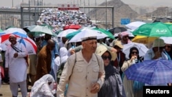 Para jemaah haji berjalan dengan payung di tengah cuaca yang sangat panas, di Mina, Arab Saudi, 18 Juni 2024. (Foto: REUTERS/Saleh Salem)