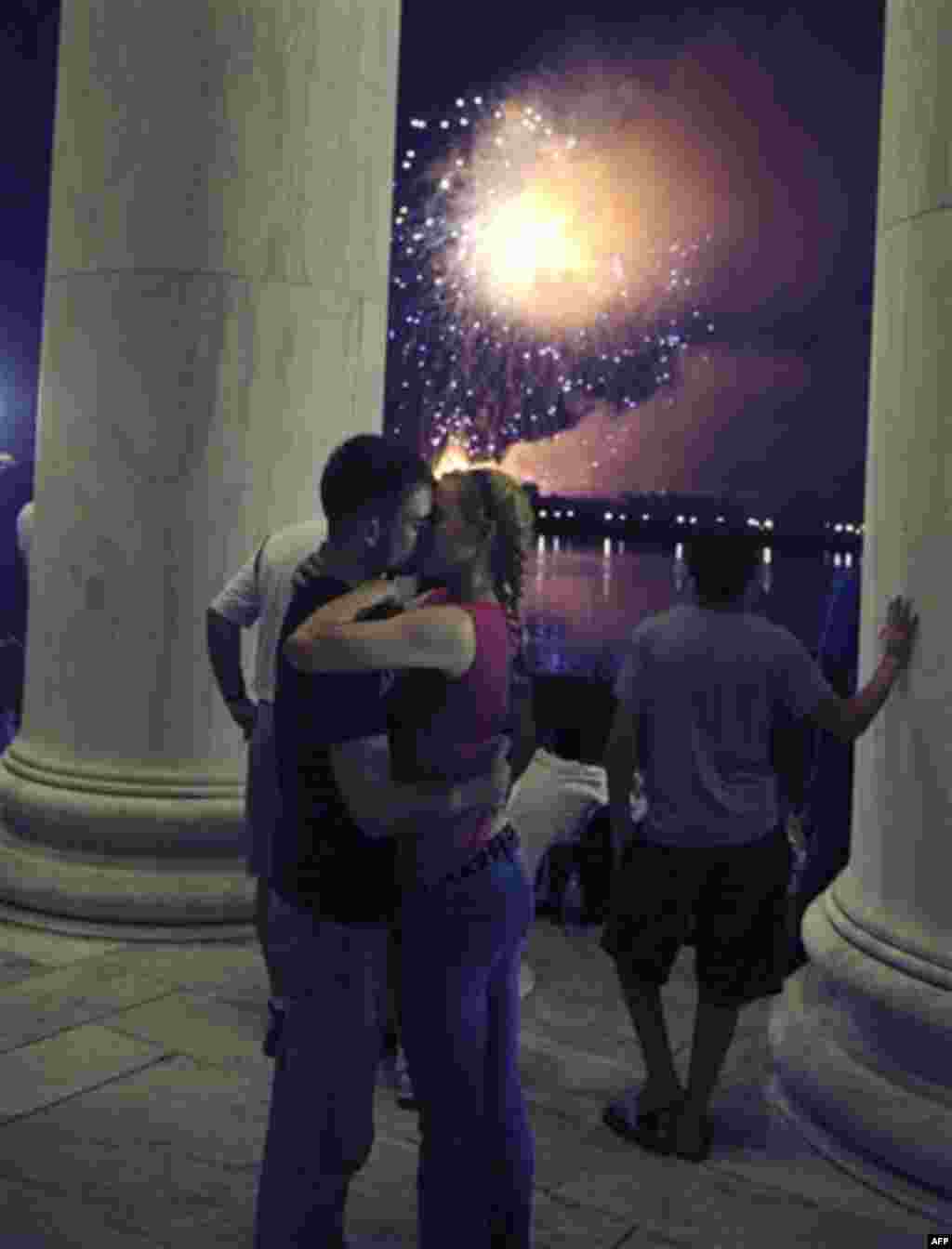 U.S. Marines Jenna Ahles, 20, of LaCrosse, Wisc., right, and Jack Eubanks, 25,of Kennesaw, Ga., kiss while fireworks explode over Washington while viewing from the Jefferson Memorial, Monday, July 4, 2011. (AP Photo/Cliff Owen)