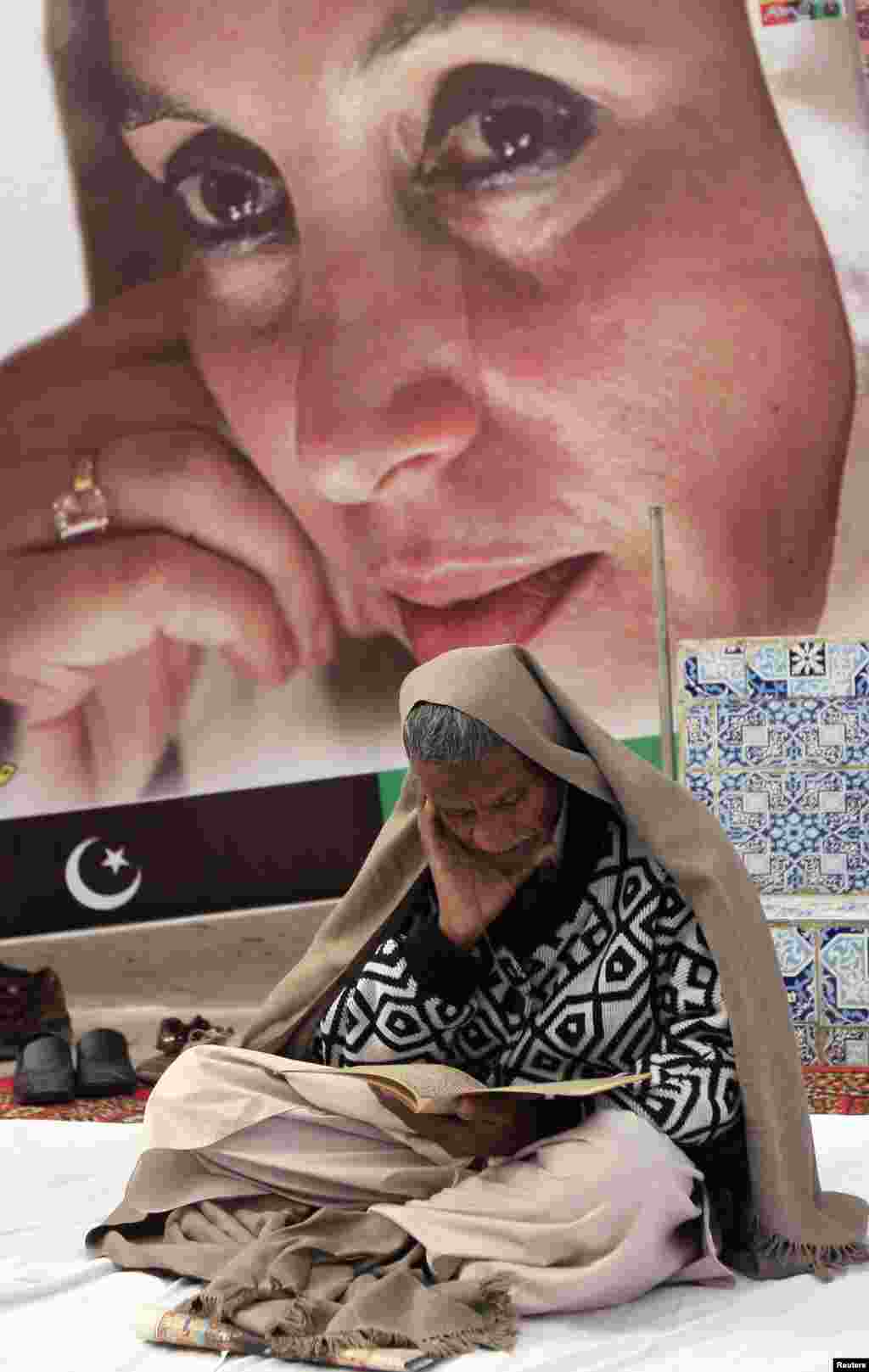 ایک کارکن بے نظیر بھٹو کی روح کے ایصال ثواب کے لیے قرآن خوانی کر رہا ہے