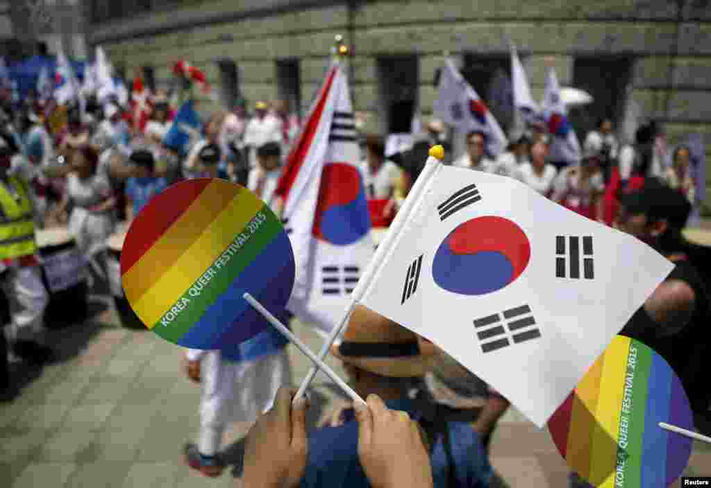 Seorang aktivis memegang kipas warna pelangi dan bendera nasional Korea Selatan, di saat para peserta festival Gay Pride menghadapi perlawanan dari kelompok Kristen, di Seoul (28/6). (Reuters/Kim Hong-Ji)