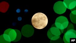 FILE - A nearly-full moon is seen among Christmas lights near Lenexa, Kansas, Dec. 24, 2015.