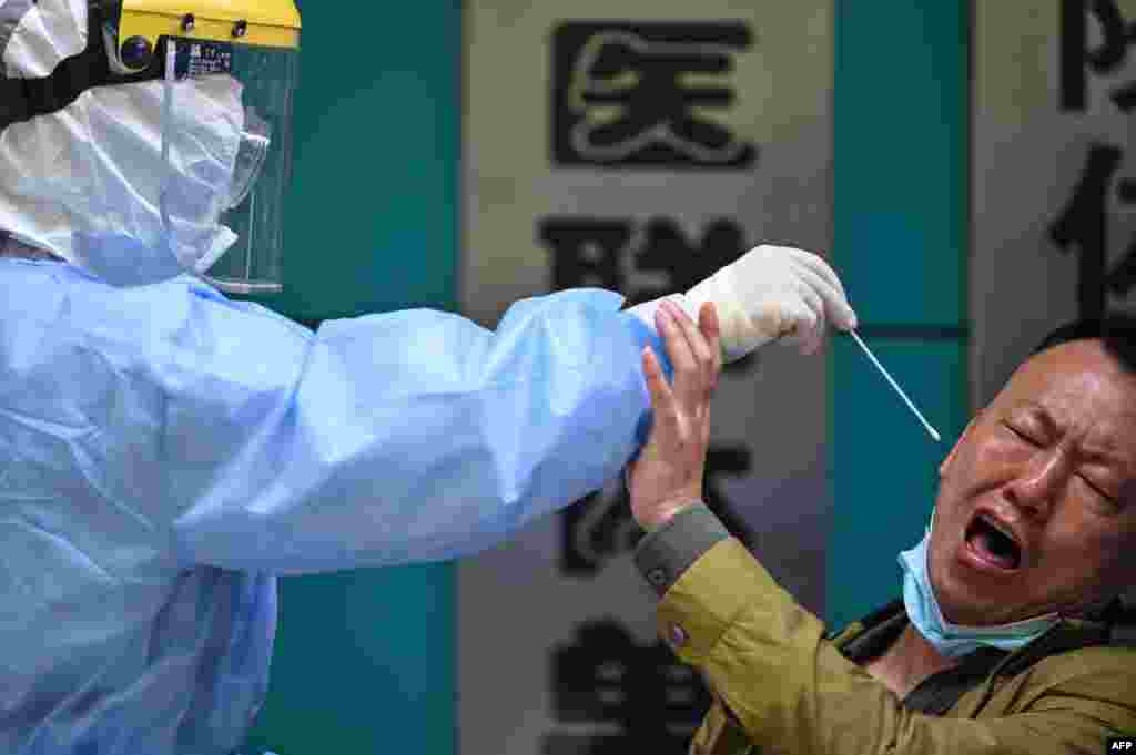 A man reacts as a medical worker takes a swab sample for the coronaviurs, in Wuhan in China's central Hubei province.