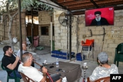 Men smoke waterpipes as they watch a televised speech by the leader of the Lebanese Shiite movement Hezbollah, Hassan Nasrallah, at a cafe in the Jabal Mehsen neighborhood of Tripoli, Lebanon, Sept. 19, 2024.