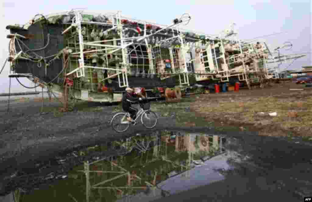 A man cycles by a ship at Hachinohe, Aomori Prefecture, northern Japan, Monday, March 14, 2011, three days after a powerful earthquake-triggered tsunami hit Japan's east coast. (AP Photo/Shizuo Kambayashi)