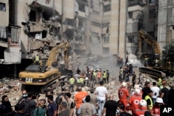 Emergency workers use excavators to clear the rubble at the site of Friday's Israeli strike in Beirut's southern suburbs, Sept. 21, 2024.