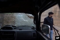 A youth inspects the wrecked truck of Tawfic Abdel Jabbar, a 17-year-old from Louisiana who was fatally shot while he was driving in the family's Palestinian home village, Al-Mazra'a ash-Sharqiya, West Bank, Jan. 23, 2024.