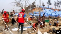 FILE - Authorities and volunteers from aid agencies rebuild shelters for Rohingya refugees who lost their dwellings to a fire at Balukhali camp at Ukhiya in Cox's Bazar district, Bangladesh, March 24, 2021. 