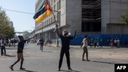 A man holds a Mozambican flag as demonstrators march during a protest against the results of the 2024 presidential election in Maputo on Nov. 2, 2024.