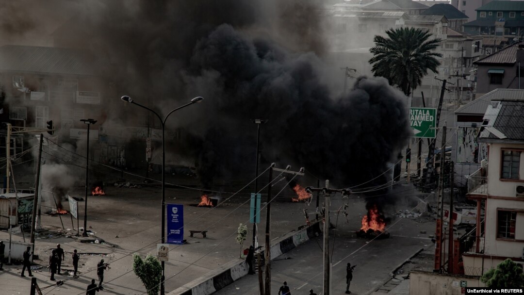 Armed men are seen near burning tires on a street in Lagos, Nigeria Oct. 21, 2020, in this image obtained from social media. (Credit: UnEarthical)