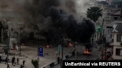 Armed men are seen near burning tires on a street in Lagos, Nigeria Oct. 21, 2020, in this image obtained from social media. (Credit: UnEarthical)