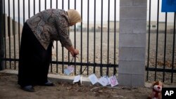 Kareema Abdul-Khabir, who teaches special needs students at an elementary school in Barstow, Calif., places some cards made by her students at a makeshift memorial honoring the victims of Wednesday's shooting rampage in San Bernardino, Dec. 4, 2015.