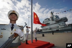 FILE - In this photo released by Xinhua News Agency, Chinese honor guard raise the Chinese flag during the commissioning ceremony of China's conventionally powered Shandong aircraft carrier at a naval port in Sanya, Hainan Province, on Dec. 17, 2019.(Li Gang/Xinhua via AP, File)