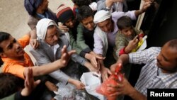 FILE - People gather to collect food rations at a food distribution center in Sana'a, Yemen, March 21, 2017.