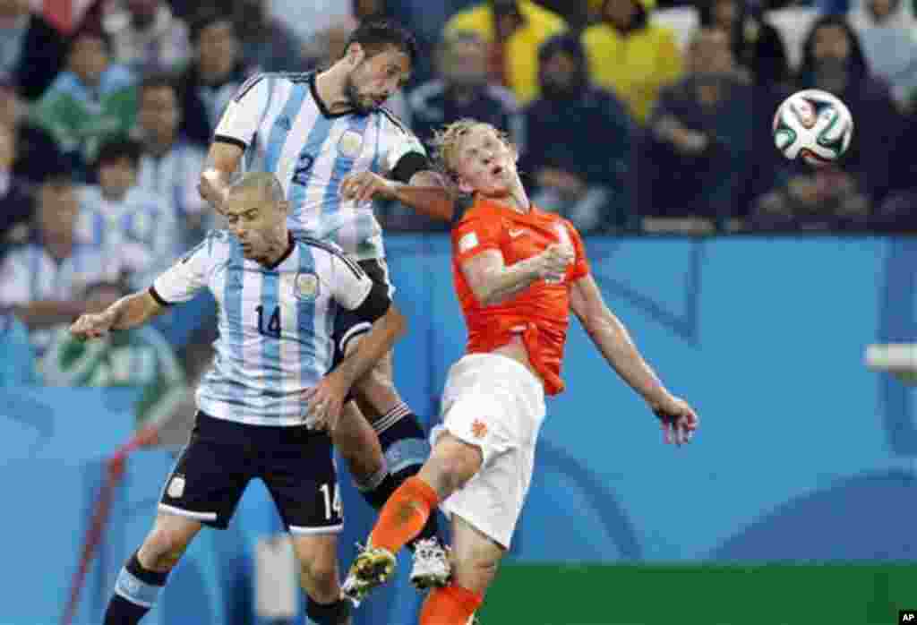 Netherlands' Dirk Kuyt, right, goes for a header with Argentina's Javier Mascherano, left, and Ezequiel Garay during the World Cup semifinal soccer match between the Netherlands and Argentina at the Itaquerao Stadium in Sao Paulo, Brazil, Wednesday, July 