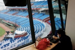A reporter waits for the game to start at an empty stadium due to the coronavirus outbreak at the first professional baseball league game of the season at Taoyuan International baseball stadium in Taoyuan city, Taiwan, April 11, 2020.