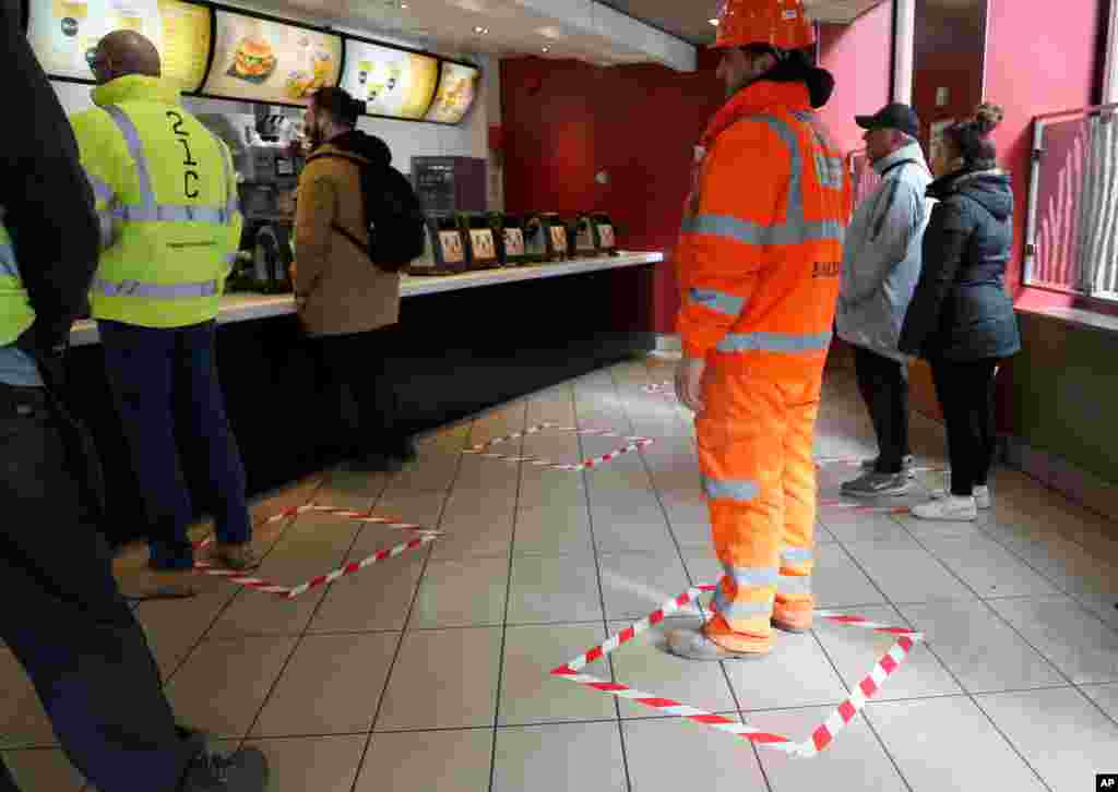 People stand in marked places to keep a proper social distance at a fast food restaurant in London.