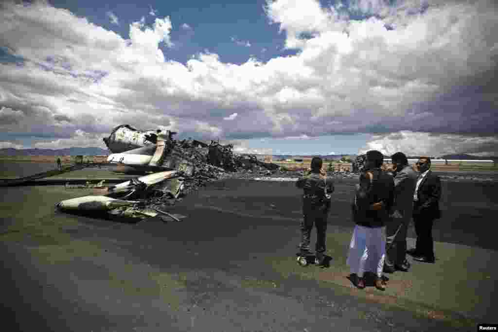 Airport officials look at the wreckage of a military transport aircraft destroyed by Saudi-led airstrikes, at the Sanaa International Airport, in Yemen. A Saudi-led coalition continues to bomb Shiite rebels known as Houthis and allied forces across the country.