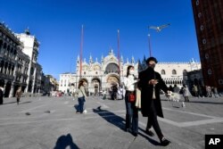 Tourists walk in St. Mark's Square in Venice, Italy, Feb. 28, 2020.