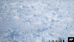 In this Aug. 16, 2019, photo, a woman stands next to an antenna at an NYU base camp at the Helheim glacier in Greenland. Summer 2019 is hitting the island hard with record-shattering heat and extreme melt.