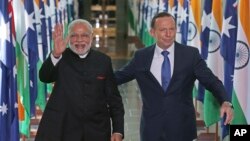 India's Prime Minister Narendra Modi, left, escorted by Australian Prime Minister Tony Abbott, waves as they leave the House of Representatives at Parliament House in Canberra, Tuesday, Nov. 18, 2014.