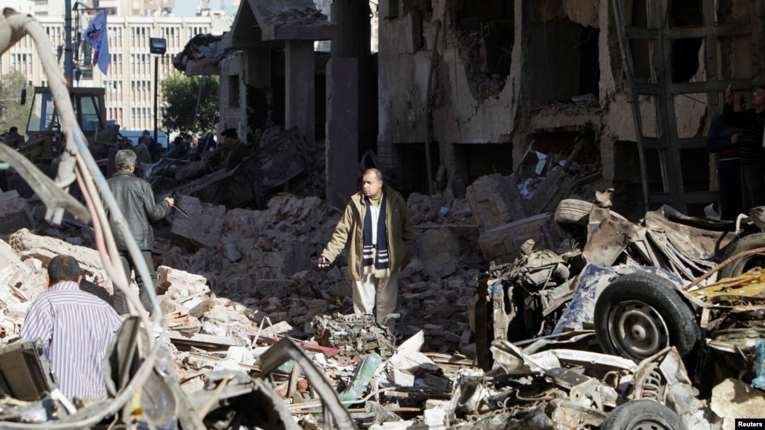 A man walks near debris after an explosion near a security building in Egypt's Nile Delta city of Mansoura in Dakahlyia province, about 120 km (75 miles) northeast of Cairo, Dec. 24, 2013.