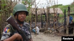 រូប​ឯកសារ៖ ទាយាន​យាម​ព្រំដែន​មីយ៉ាន់ម៉ា​ម្នាក់​ឈរ​យាម​នៅ​ពី​មុខ​ផ្ទះ​ដែល​ឆាបឆេះ​នៅ​ក្នុង​ការ​ប៉ះទង្គិច​រវាង​ក្រុម​យុទ្ធជន និង​កងកម្លាំង​សន្តិសុខ​នៅ​ក្នុង​ភូមិ Tin May រដ្ឋ Rakhine ប្រទេស​មីយ៉ាន់ម៉ា កាលពី​ថ្ងៃទី១៤ ខែកក្កដា ឆ្នាំ២០១៧។