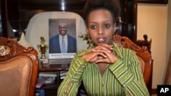 In this photo taken May 14, 2017, women's rights activist and presidential candidate Diane Rwigara, 35, is photographed next to a portrait of her father, business tycoon Assinapol Rwigara, at her home in Kigali, Rwanda.