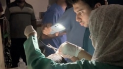 Doctors treat an injured man using mobile phone flashlight in Gaza