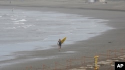 A surfer walks alone on Katase Kaigan beach in Fujisawa, near Tokyo, July 7, 2020. 