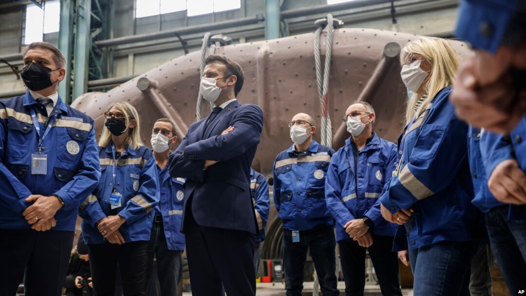 Presiden Prancis Emmanuel Macron (tengah) berdiri di antara para pekerja ketika berkunjung ke lokasi pembangkit listrik tenaga uap GE Steam Power System di Belfort, di bagian timur Prancis, pada 10 Februari 2022. (Foto: AP/Jean-Francois Badias)