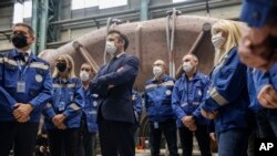 French President Emmanuel Macron, center, stands among workers as he visits the GE Steam Power System main production site for its nuclear turbine systems, in Belfort, eastern France, Feb. 10, 2022.