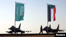 FILE - Military personnel walk past the flags of Saudi Arabia and Sudan at Merowe Airport in Merowe, Northern State, Sudan, April 9, 2017. 