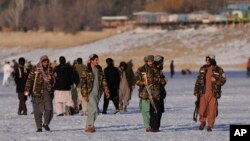 Taliban fighters walk at the frozen Qargha Lake, near Kabul, Afghanistan, Feb. 11, 2022. The Taliban have released from custody two foreign journalists and their local colleagues after "verifying their identities."