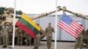 FILE - Soldiers hold Lithuanian and US flags during the opening ceremony of the US army camp Herkus in Pabrade, Lithuania, Aug. 30, 2021.