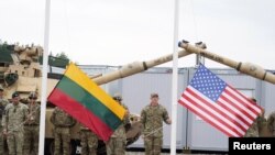 فائل فوٹو - 30 اگست 2021 کو پابراڈ، لتھوانیا میں امریکی فوجی کیمپ ہرکس کی افتتاحی تقریب کے دوران سپاہی لتھوانیا اور امریکی پرچم تھامے ہوئے ہیں۔
